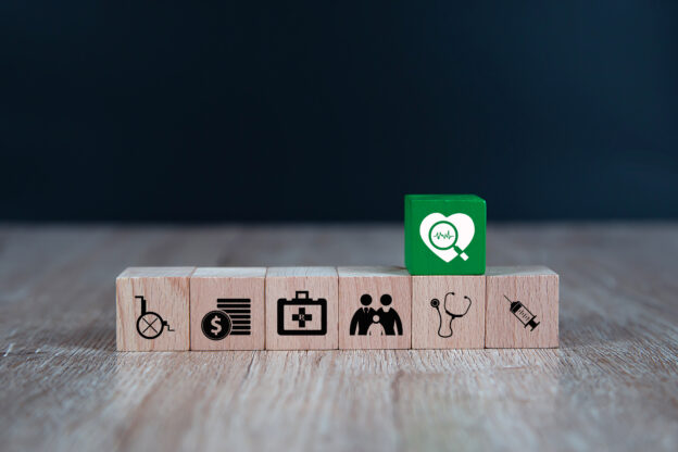 Wooden toy blocks stacked with medical icon for medical and health insurance concepts.